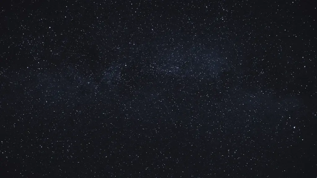 Ein klarer, nächtlicher Sternenhimmel über einer ruhigen Landschaft in Deutschland bei Nacht.